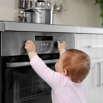 Little child playing with electric stove in the kitchen